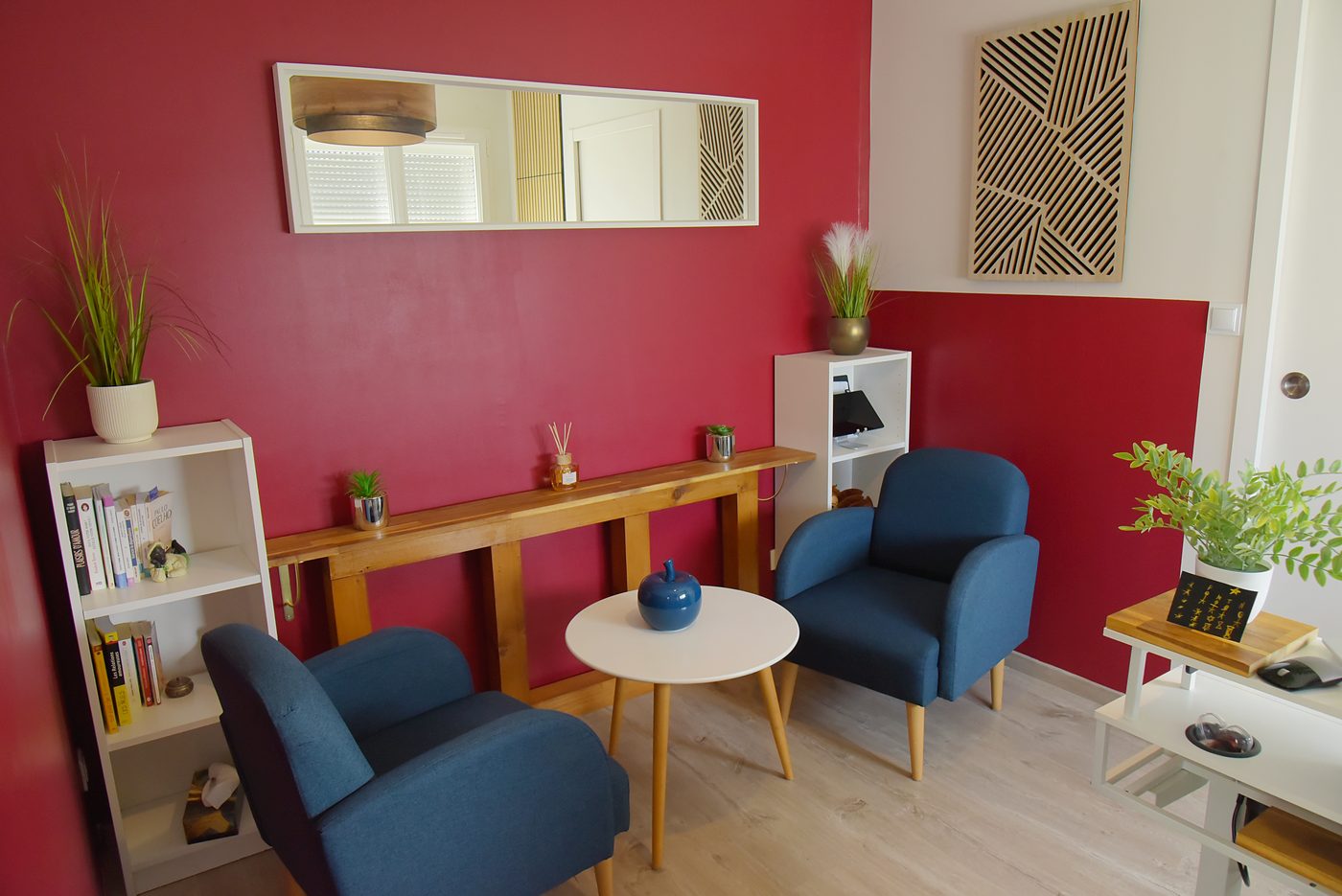 Cabinet de coaching SENSIUM à La Roche-sur-Yon : deux fauteuils bleus autour d'une table ronde, mur framboise